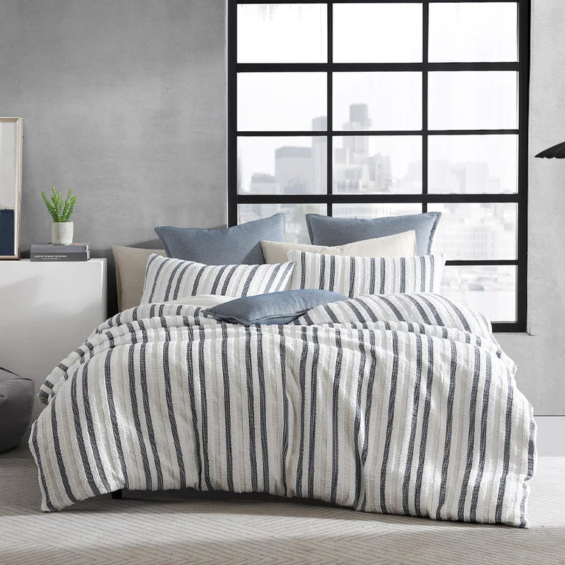 Experience the harmonious blend of soft chenille and a navy and white geometric design in a lineal pattern with the Boston Quilt Cover Set Range White by Logan and Mason Platinum.