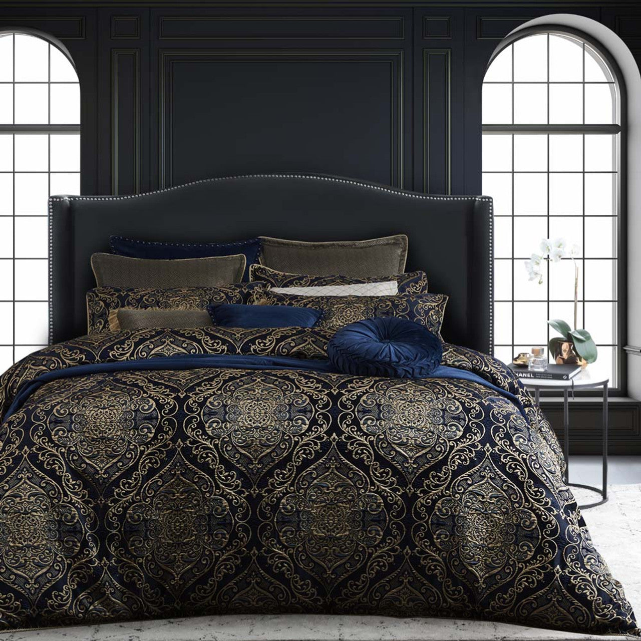 Experience the allure and grandeur of French Rococo design with the Davinci Peron Night Bed Quilt Cover Set. This exquisite ensemble pays homage to the decadence and drama of the era. The formal and symmetrical composition showcases large ornamental motifs enriched with metallic gold threads, set against a deep navy ground. 