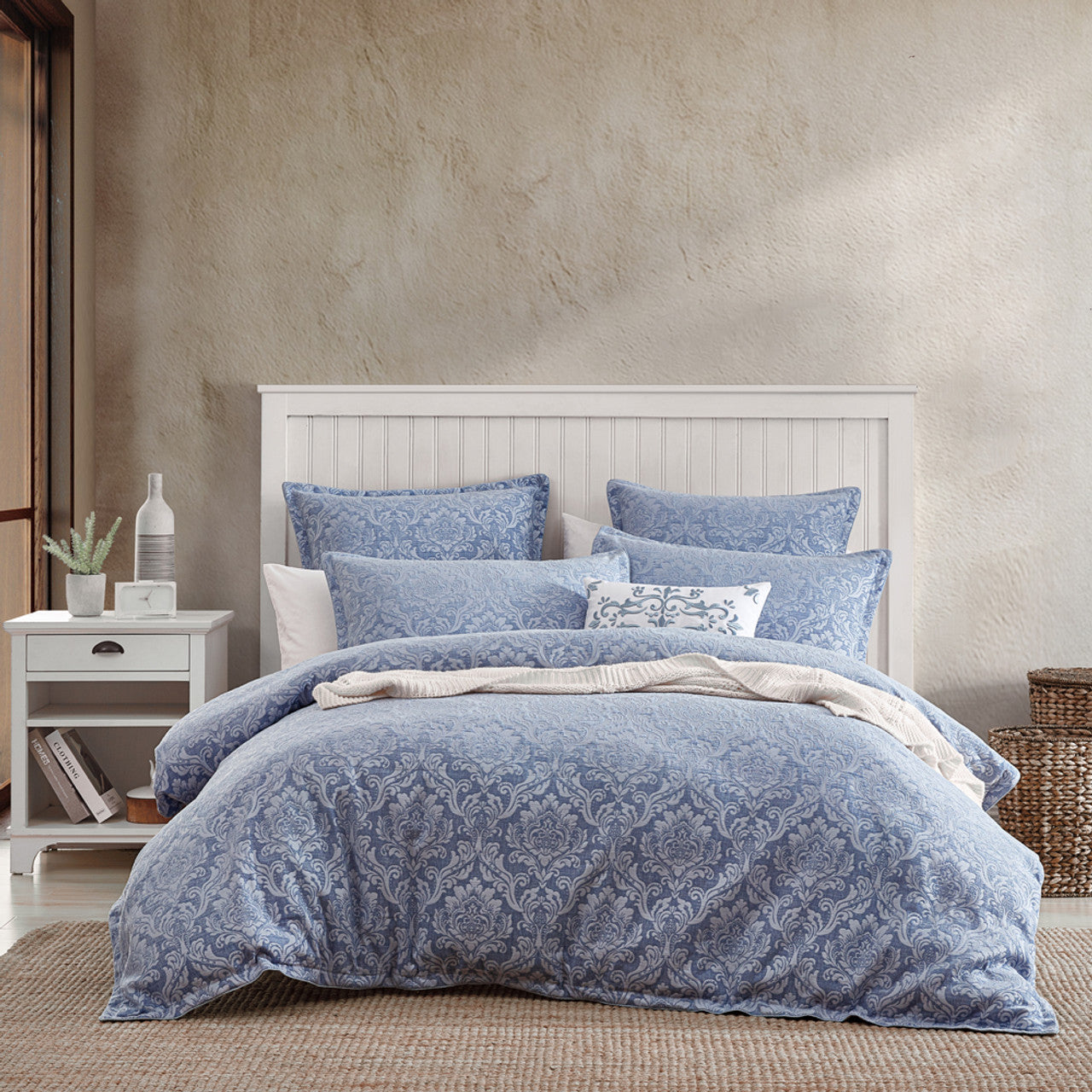 The Monterey Wedgwood bed quilt cover set from the Private Collection showcases a vintage French damask design with a touch of nostalgia. The soft and warm chenille fabric serves as a backdrop, creating a harmonious blend of tonal blues. 