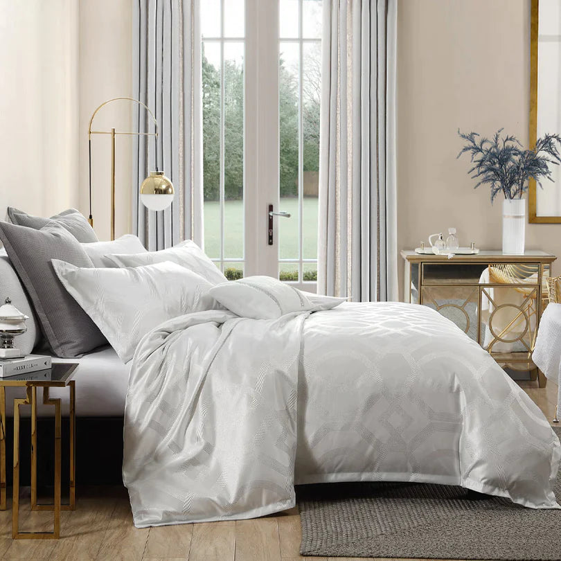 Elevate the allure of your bedroom with the captivating Hollywood glamour of Seville Snow. This remarkable collection showcases a striking geometric pattern crafted with metallic yarn, ensuring that Seville exudes a radiant sparkle from every angle.