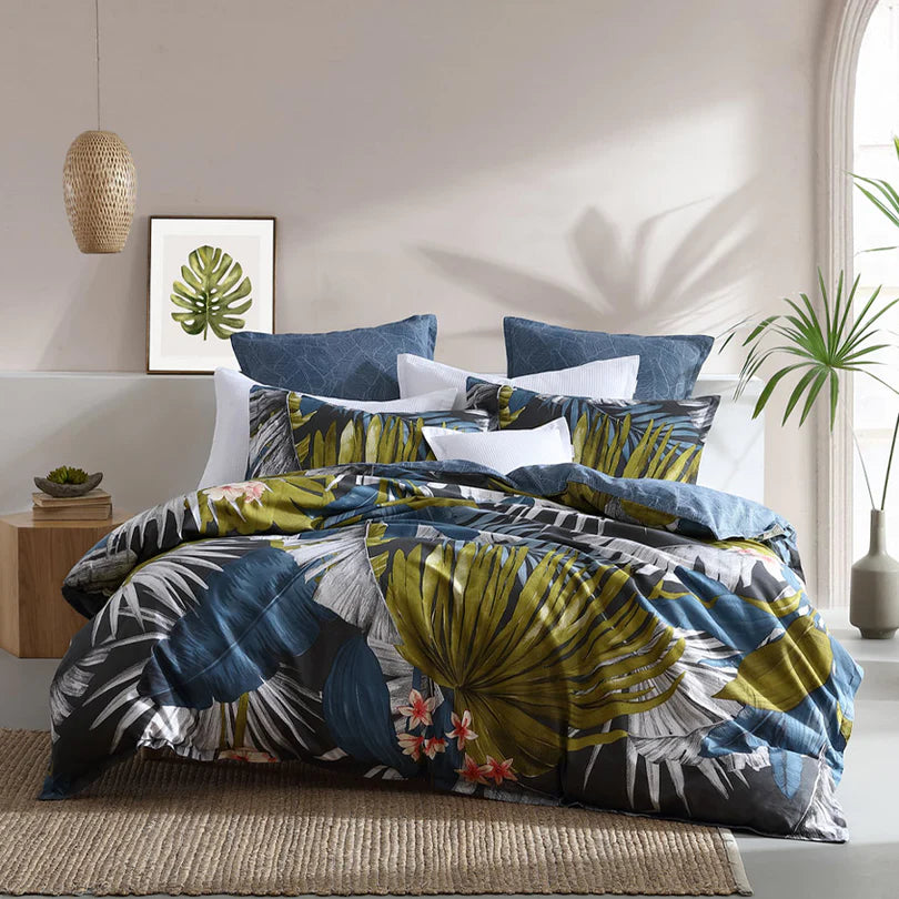 Escape to a winter tropical paradise with the Mira Quilt Cover Set Range Pepper by Logan and Mason. This exquisite bedding set showcases oversized hand-drawn palm leaves in captivating shades of teal, denim, and chartreuse, elegantly set against a charcoal backdrop with vibrant pops of orange floral accents