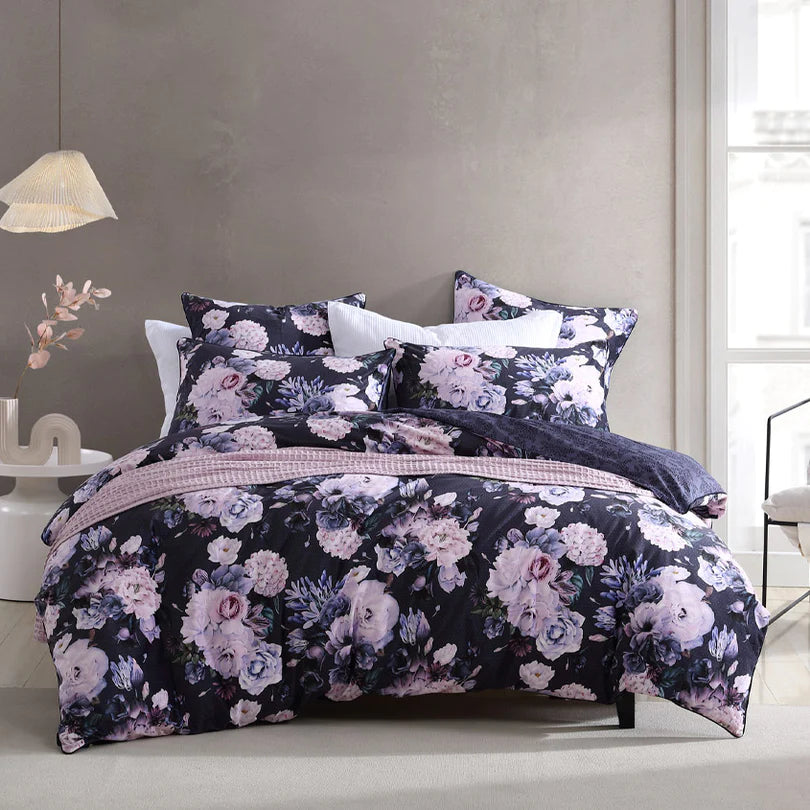 Experience the captivating beauty of the Macy Quilt Cover Set Range Violet by Logan and Mason Platinum, showcasing winter bouquets of stunning blooms printed on luxuriously soft velvet. 
